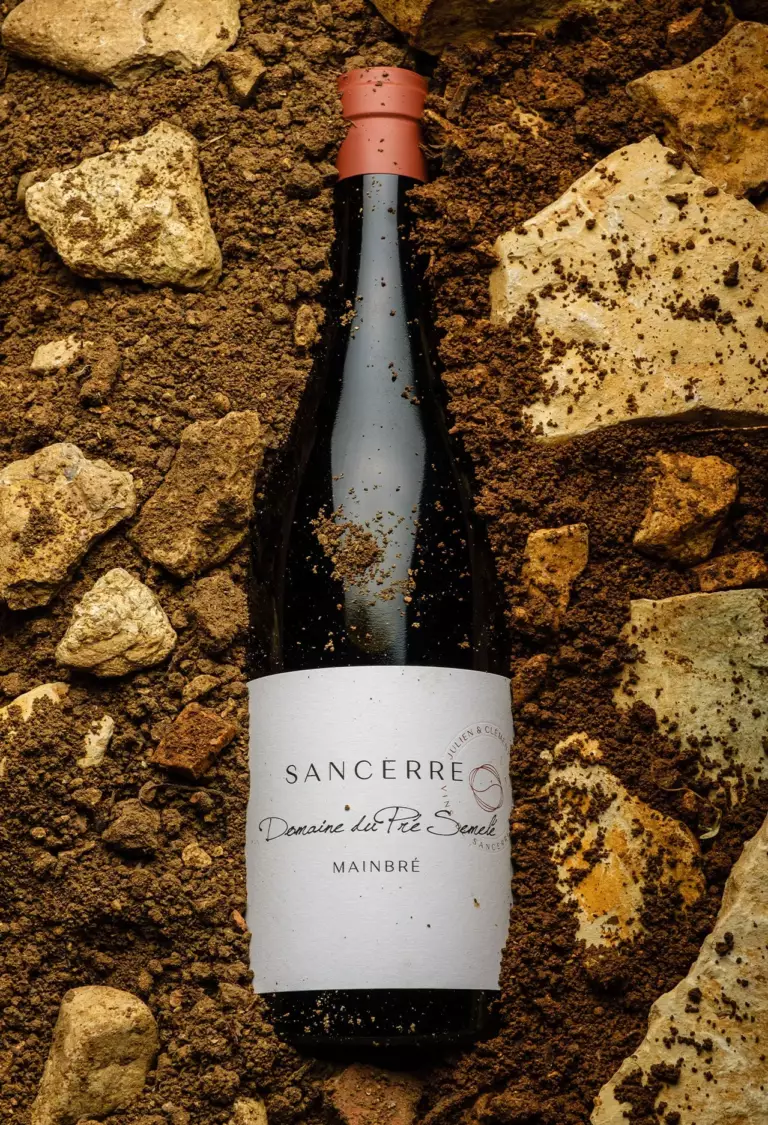 Bouteille de Mainbré Rouge posée sur le terroir du Domaine du Pré Semelé